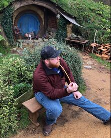 Man using a fake pipe near a hobbit house Picture