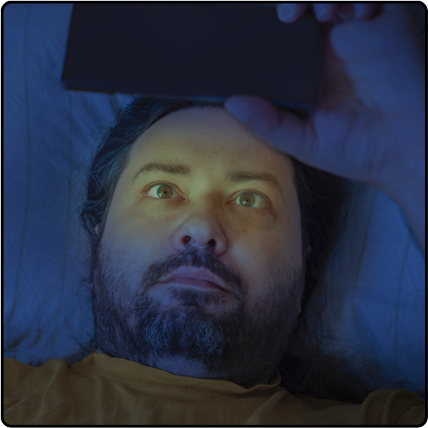 Man suffering from insomnia using his phone in bed Picture